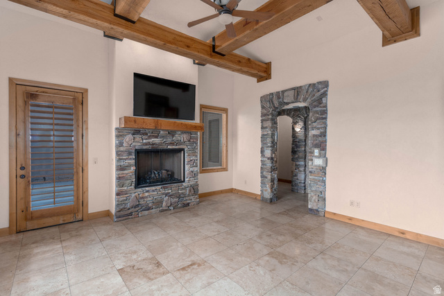 2464 East Granite Way St. George, UT 84790 - Photo 76 of 106 Unfurnished living room featuring ceiling fan, beam ceiling, and a fireplace