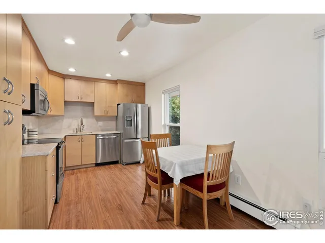 a kitchen with stainless steel appliances kitchen island granite countertop a refrigerator a stove a sink dishwasher and white cabinets with wooden floor