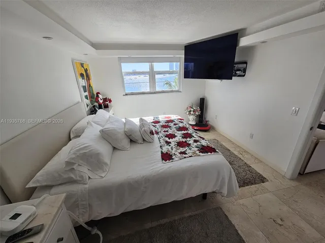 a bedroom with a bed a flat screen tv and window