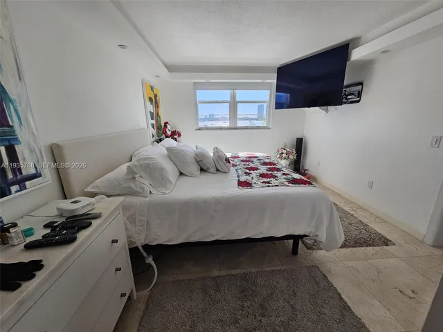 a bedroom with a bed a couch and a flat screen tv