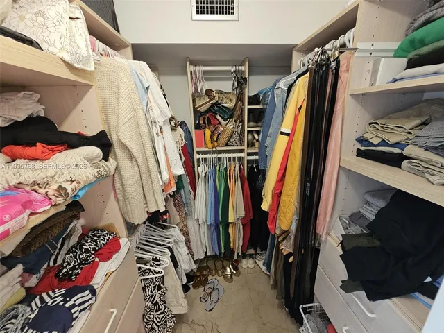 a view of walk in closet with clothes and shoes