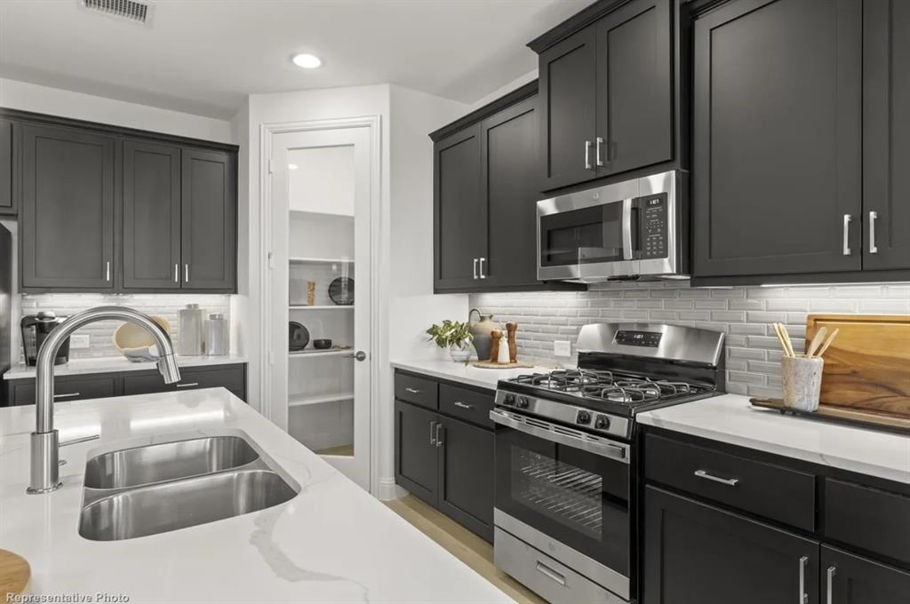 2504 Sturgis Street Forney, TX 75126 - Photo 7 of 24 a kitchen with granite countertop a sink a stove and refrigerator
