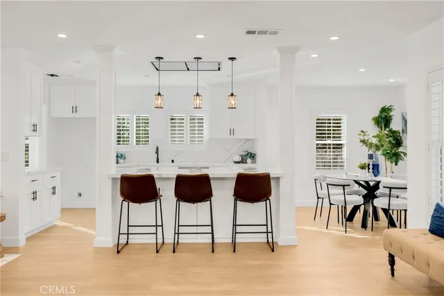 a very nice looking open kitchen with stainless steel appliances granite countertop a sink dishwasher a stove and a dining table with wooden floor