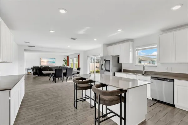 a kitchen with stainless steel appliances a table chairs refrigerator and cabinets