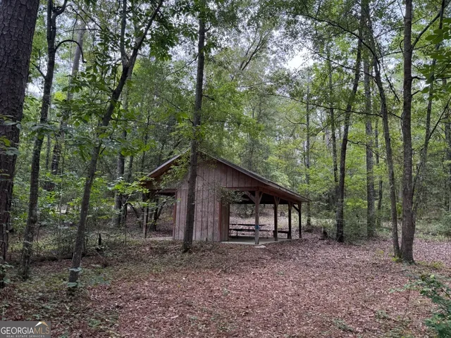 a view of wooden house with a yard and large trees