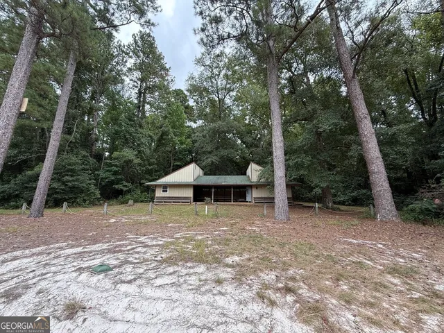 a front view of house with yard and trees in the background