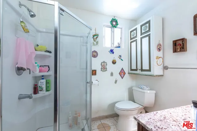 a bathroom with a granite countertop sink a mirror and shower