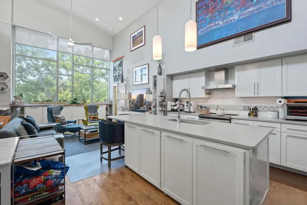 a kitchen with stainless steel appliances granite countertop a stove a sink dishwasher and white cabinets with wooden floor