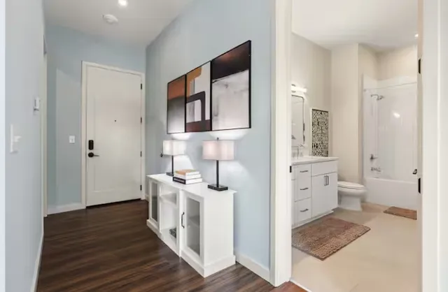 a kitchen with stainless steel appliances granite countertop a sink a stove a refrigerator a microwave oven with white cabinets and wooden floor