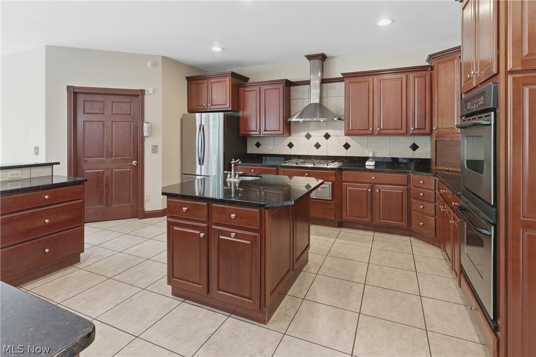 2184 Brenner Road Northeast Carrollton, OH 44615 - Photo 9 of 50 Kitchen featuring rich wood cabinetry, dark stone countertops, stainless steel appliances, a center island with sink, and tile flooring