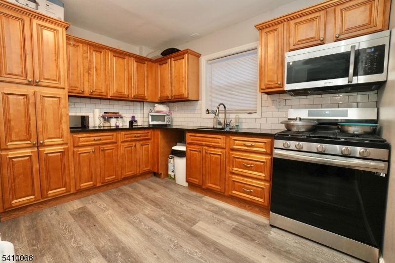 172 Delavan Avenue Newark, NJ 07104 - Photo 12 of 16 a kitchen with stainless steel appliances granite countertop a stove a sink dishwasher and a microwave oven with wooden floor