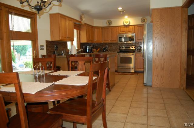 1261 Miller Road Wind Gap, PA 18091 - Photo 4 of 24 a kitchen with stainless steel appliances kitchen island granite countertop a refrigerator a stove a sink a dining table and chairs with wooden floor