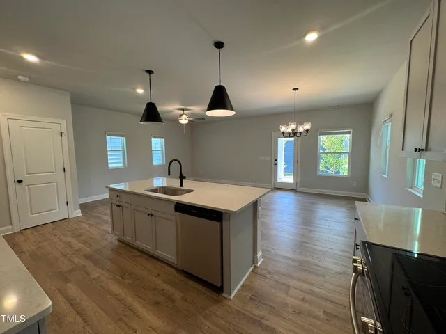 a kitchen with stainless steel appliances granite countertop a sink a stove and a wooden floors