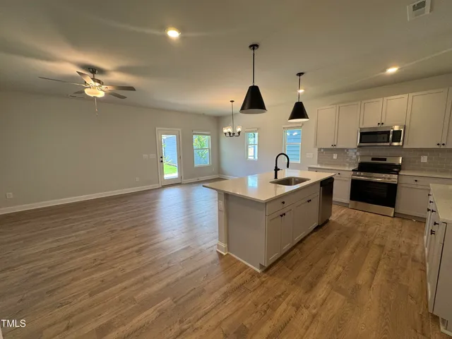 a kitchen with stainless steel appliances granite countertop a sink a stove and a wooden floors
