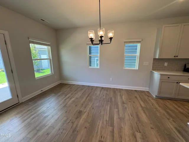 a view of a room with wooden floors and chandelier