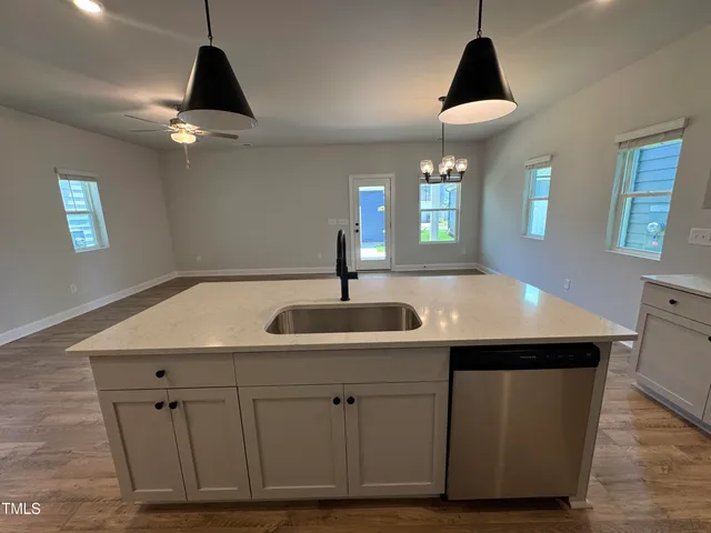 a kitchen with a sink chandelier and wooden floor