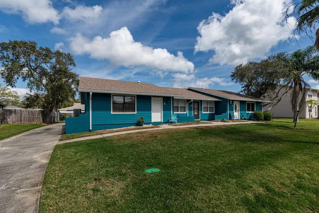 a front view of a house with a garden and trees