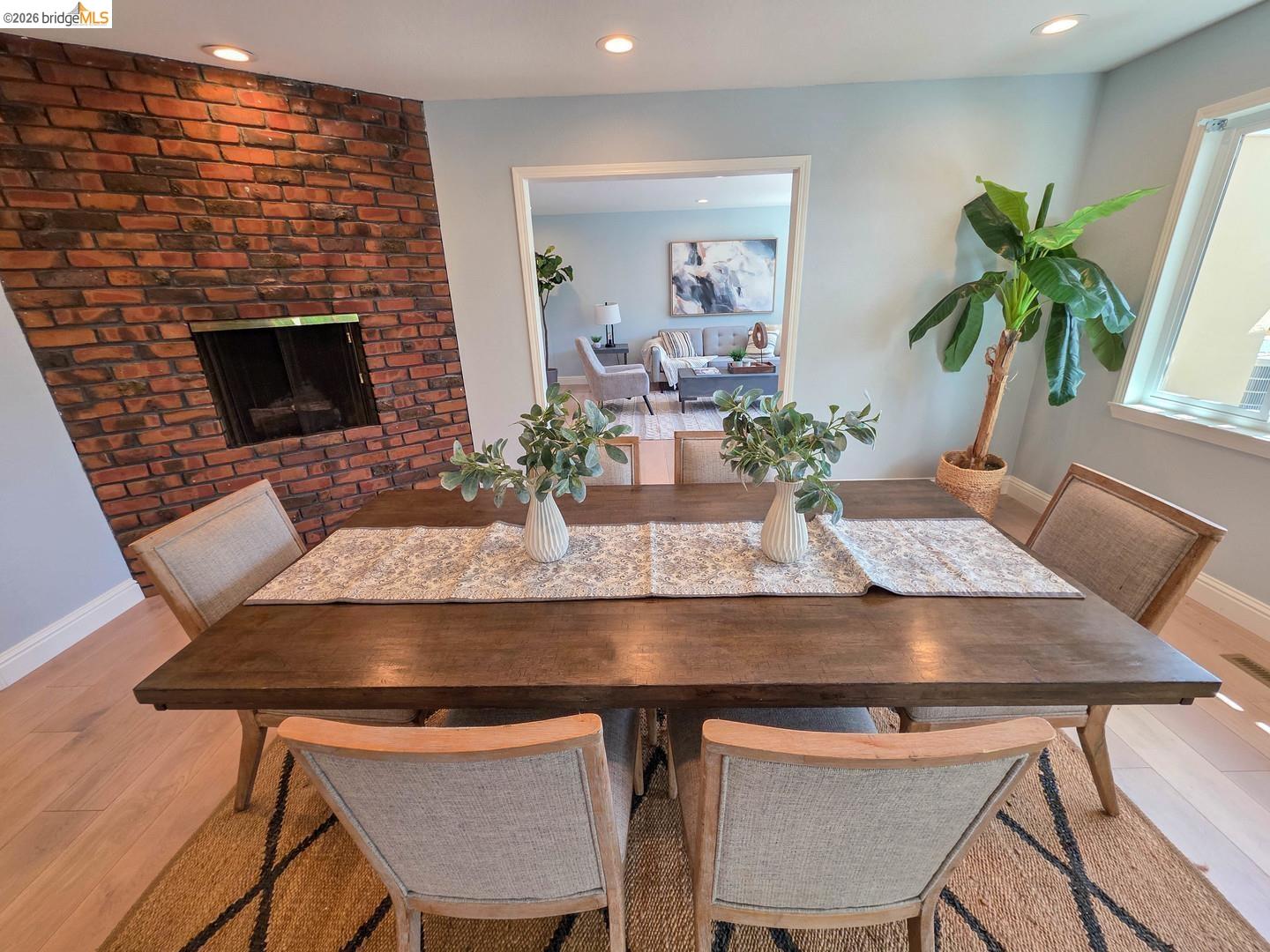 965 Springer Road Los Altos, CA 94024 - Photo 10 of 31 Dining space featuring a wood-finish table, exposed brick fireplace, recessed lighting, and hardwood flooring