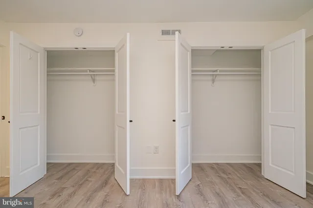 a view of an empty walk in closet with wooden floor