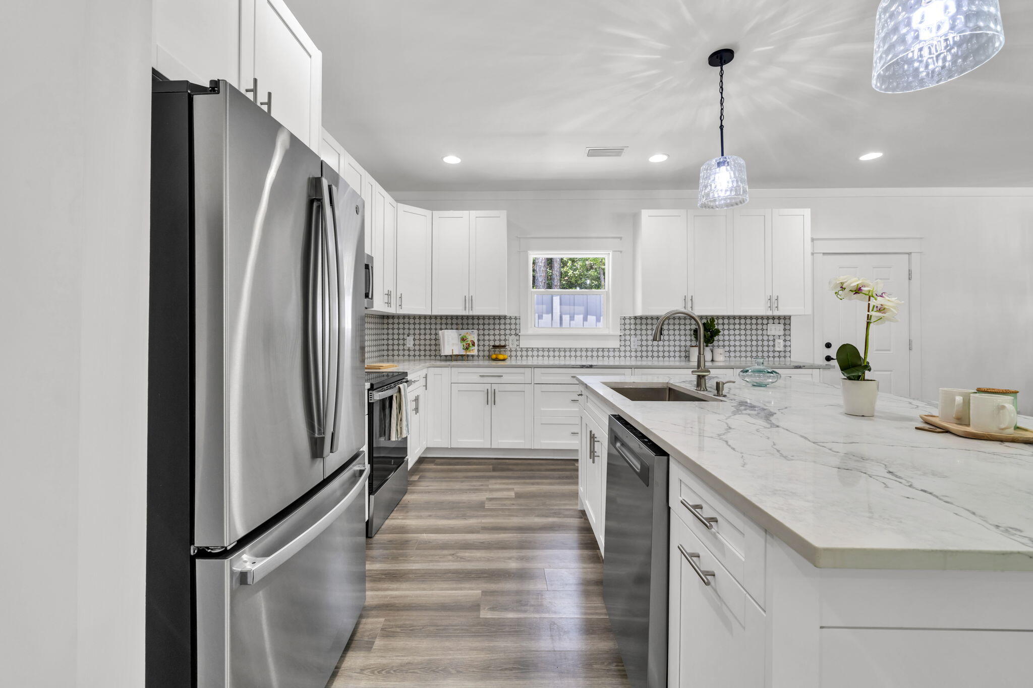 2672 Chat Holley Road Santa Rosa Beach, FL 32459 - Photo 17 of 53 a kitchen with stainless steel appliances granite countertop a refrigerator a sink dishwasher a stove and white cabinets with wooden floor