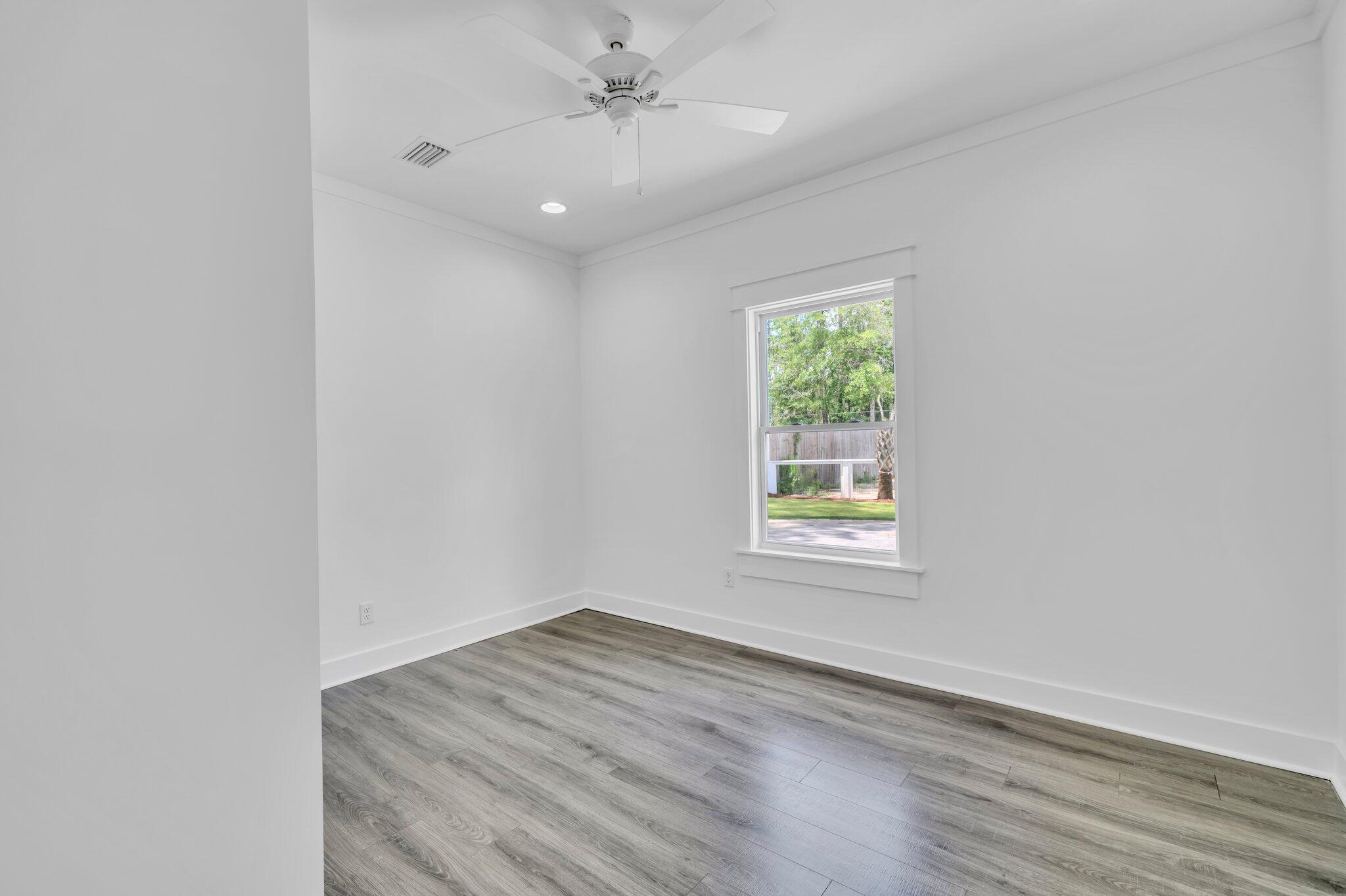 2672 Chat Holley Road Santa Rosa Beach, FL 32459 - Photo 34 of 53 an empty room with wooden floor ceiling fan and window