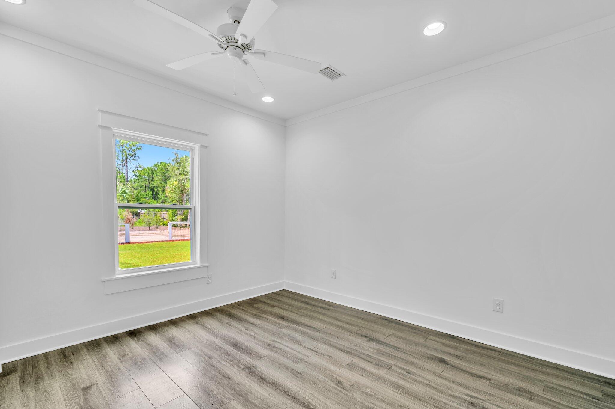 2672 Chat Holley Road Santa Rosa Beach, FL 32459 - Photo 38 of 53 an empty room with wooden floor ceiling fan and windows