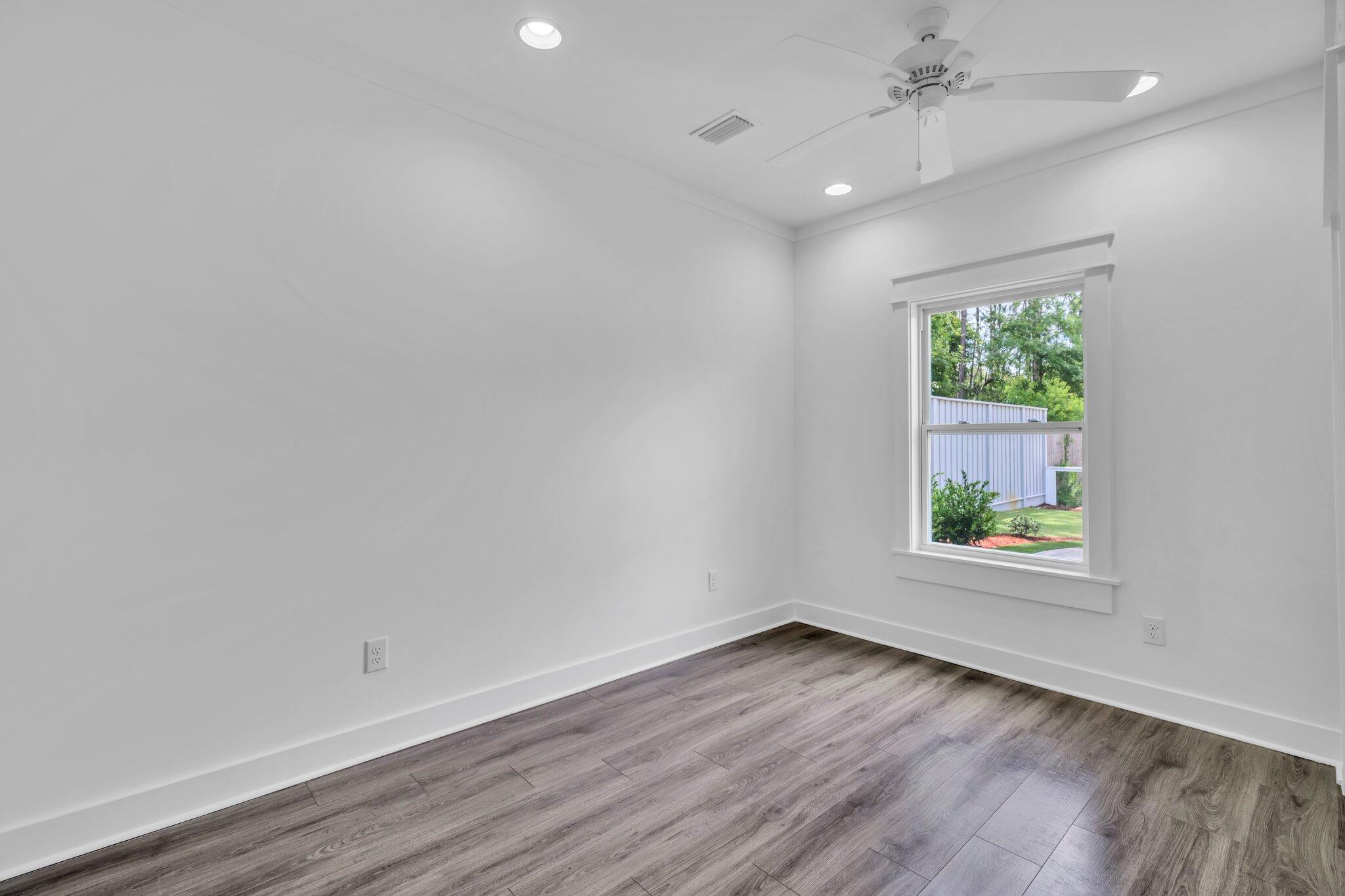 2672 Chat Holley Road Santa Rosa Beach, FL 32459 - Photo 41 of 53 an empty room with wooden floor a ceiling fan and windows