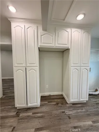 an empty room with wooden floor and cabinets