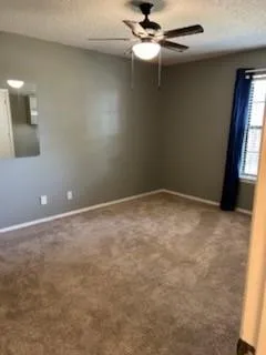 an empty room with a window and a fan