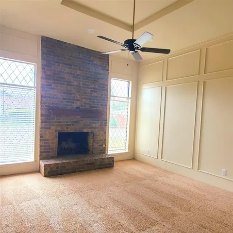 an empty room with windows fireplace and a ceiling fan
