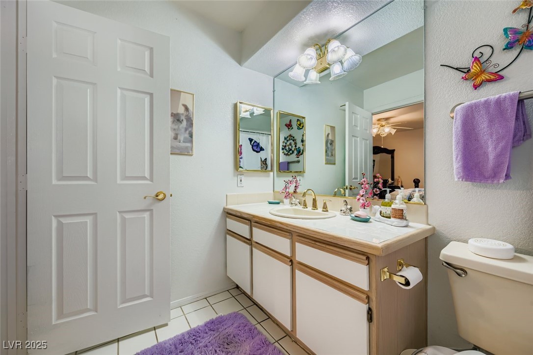 6800 West Elm Creek Drive, Unit 103 Las Vegas, NV 89108 - Photo 17 of 22 Half bathroom with light tile patterned floors, vanity, a chandelier, and ceiling fan