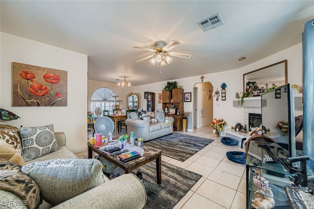 6800 West Elm Creek Drive, Unit 103 Las Vegas, NV 89108 - Photo 7 of 22 Living area with tile patterned flooring, arched walkways, a chandelier, a ceiling fan, and a tiled fireplace