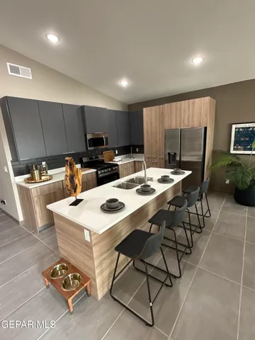 a kitchen with stainless steel appliances kitchen island granite countertop a sink a stove a refrigerator cabinets and chairs