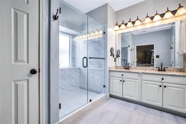 a spacious bedroom with a bed and a lamp on dresser