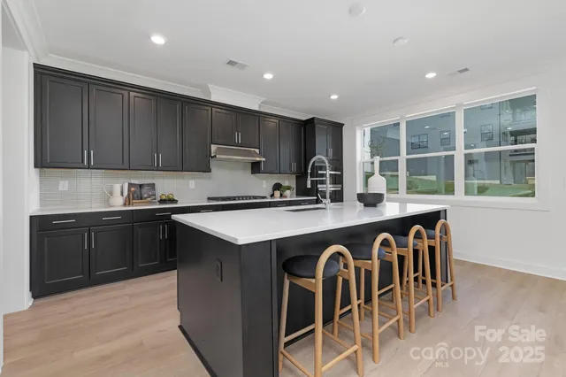 a kitchen with kitchen island granite countertop a stove a sink a microwave and wooden cabinets