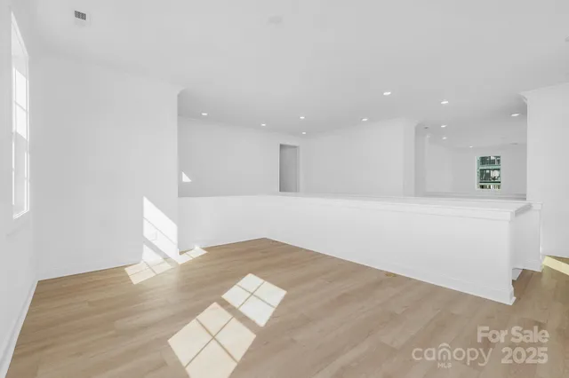 a view of kitchen and empty room with wooden floor