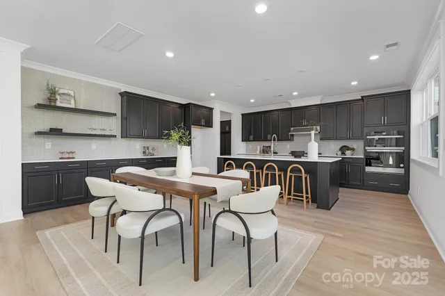 a kitchen with stainless steel appliances kitchen island granite countertop a table chairs sink and cabinets