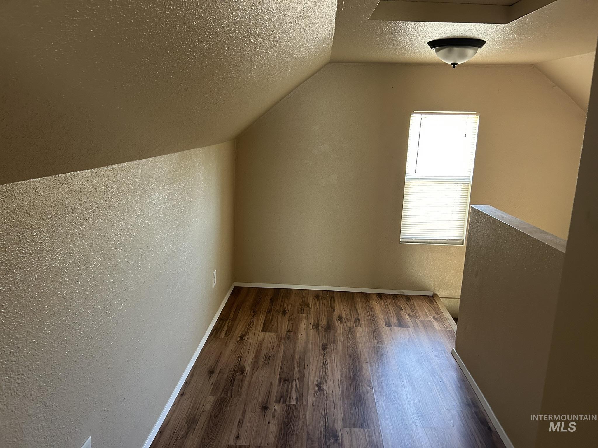 1413 7th Avenue Lewiston, ID 83501 - Photo 11 of 15 Bonus room with a textured wall, a textured ceiling, dark wood-style flooring, and vaulted ceiling