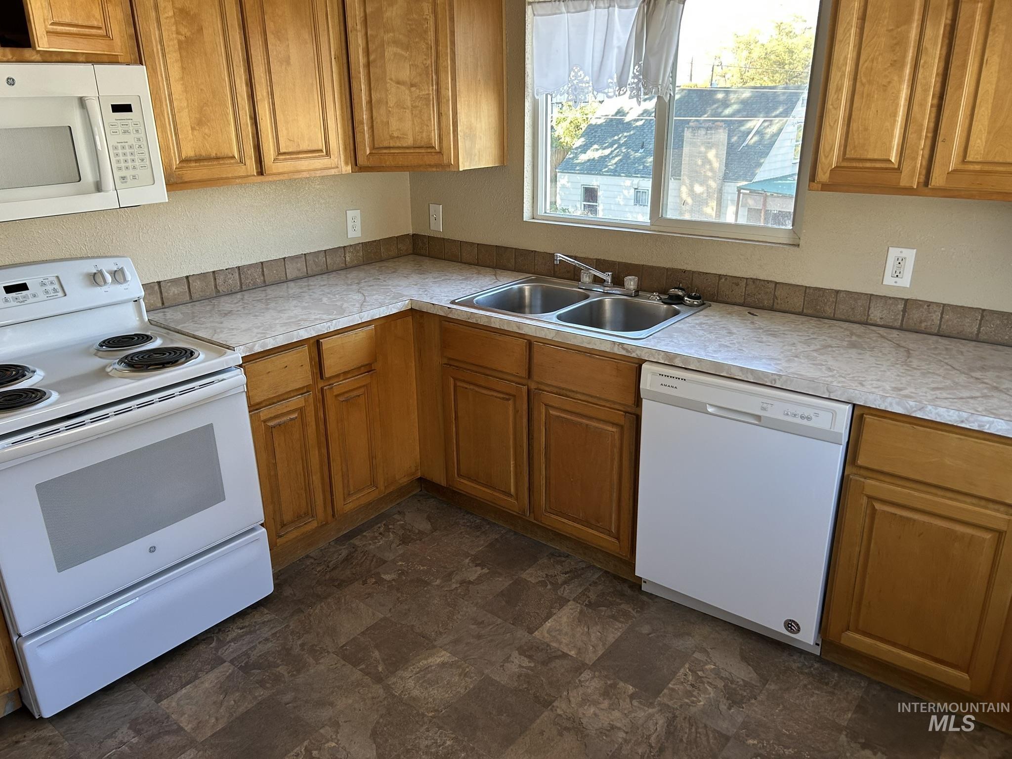 1413 7th Avenue Lewiston, ID 83501 - Photo 7 of 15 Kitchen with white appliances, brown cabinets, light countertops, and stone finish floors