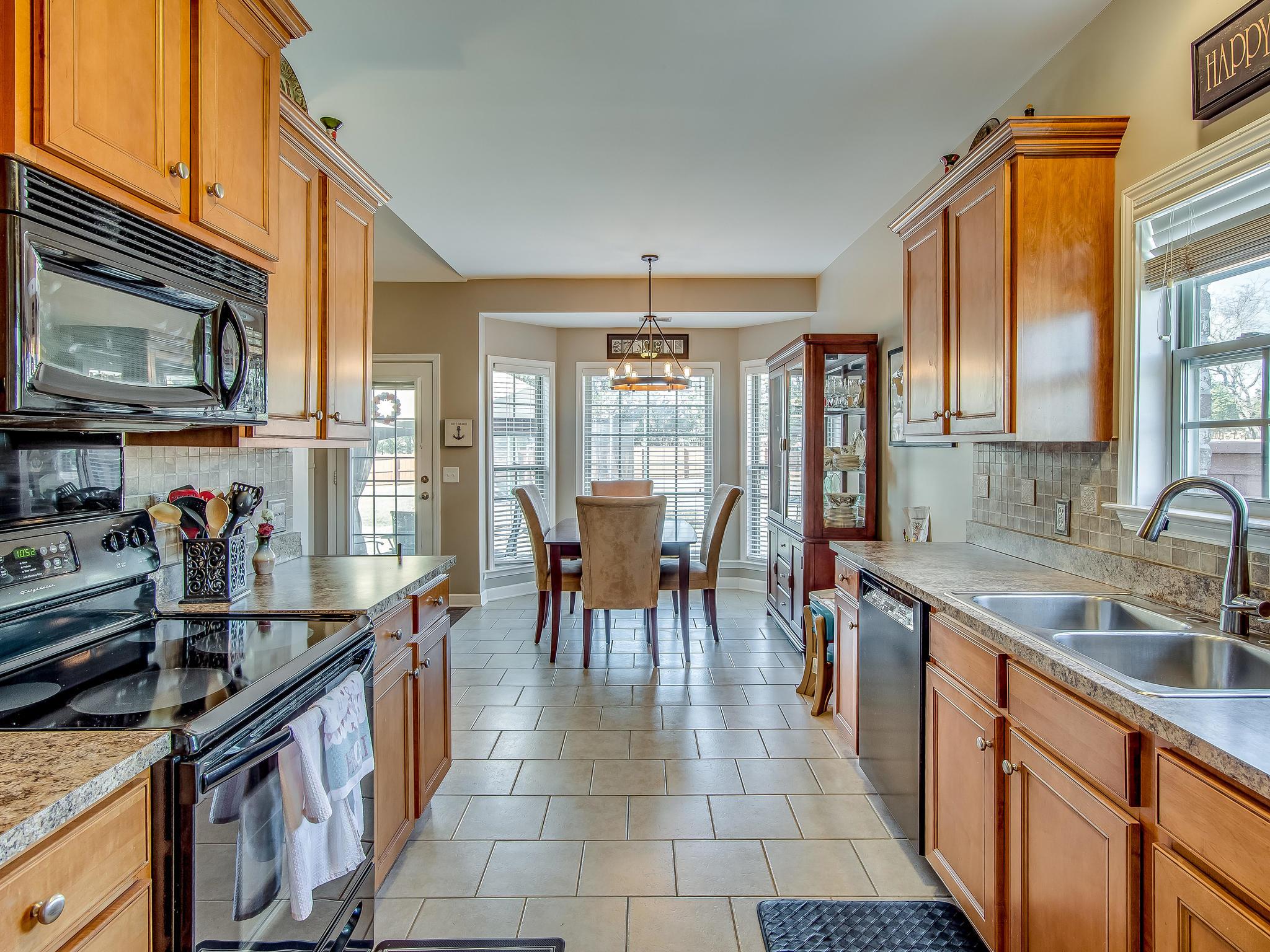 413 Reagan Road Mount Juliet, TN 37122 - Photo 14 of 30 a open kitchen with stainless steel appliances granite countertop a stove top oven a sink dishwasher a dining table and chairs with wooden floor