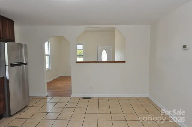 a view of a livingroom with wooden floor and a refrigerator