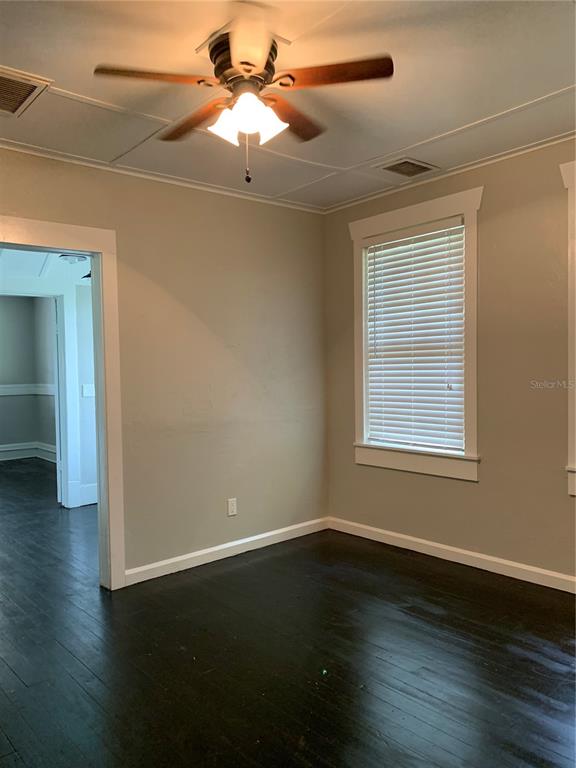 210 West Wisconsin Avenue, Unit B Deland, FL 32720 - Photo 4 of 7 an empty room with wooden floor fan and windows