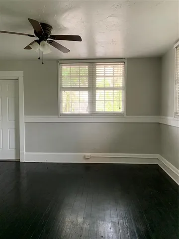an empty room with wooden floor and windows with curtains