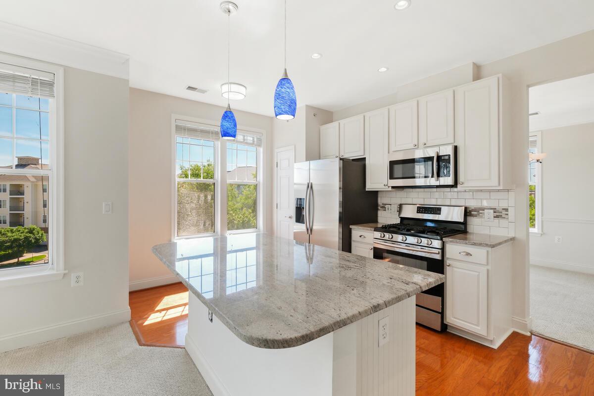 130 Chevy Chase Street, Unit 404 Gaithersburg, MD 20878 - Photo 18 of 39 a kitchen with stainless steel appliances granite countertop a sink a stove a microwave a refrigerator and cabinets