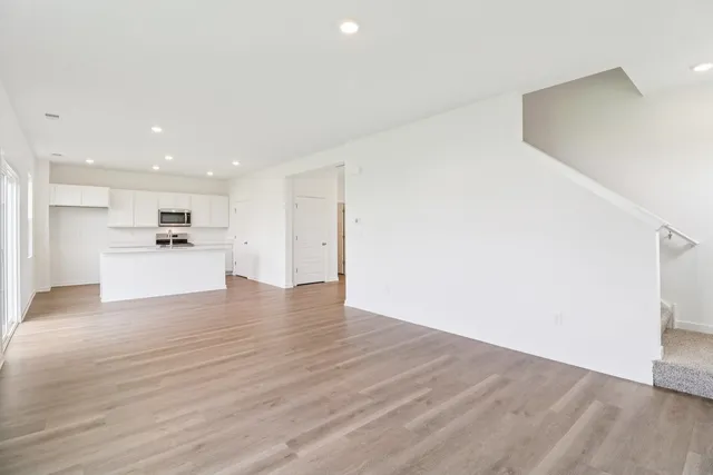 a kitchen with stainless steel appliances granite countertop a sink stove refrigerator and white cabinets with wooden floor