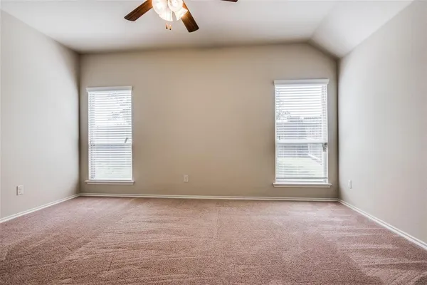 an empty room with chandelier fan and windows