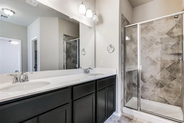 a bathroom with a double vanity sink mirror and shower