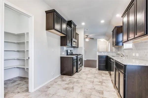 a large kitchen with stainless steel appliances granite countertop a refrigerator and a stove top oven