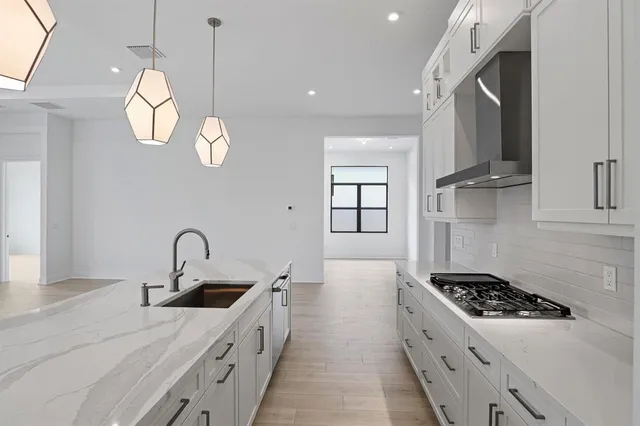 a kitchen with stainless steel appliances granite countertop a sink a stove and a wooden floors
