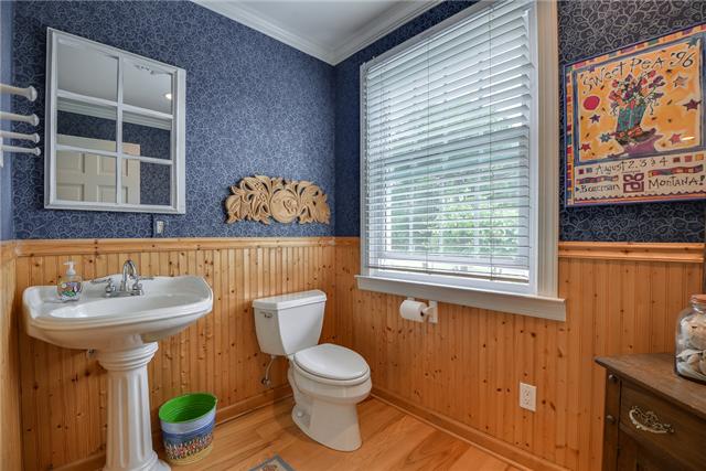 968 Sneed Road West Franklin, TN 37069 - Photo 12 of 20 This cute half bathroom on the main floor has tongue and groove wall paneling, crown molding, hickory hardwood flooring, and white fixtures with a pedestal sink.